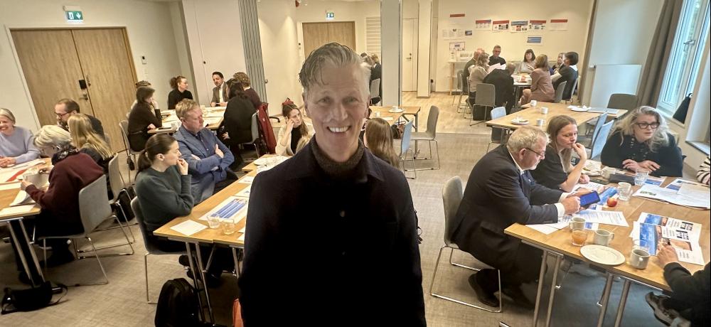 Michael Persson Gripkow var inbjuden att föreläsa och leda workshoppen. Michael Persson Gripkow framför grupper av personer i ett konferensrum