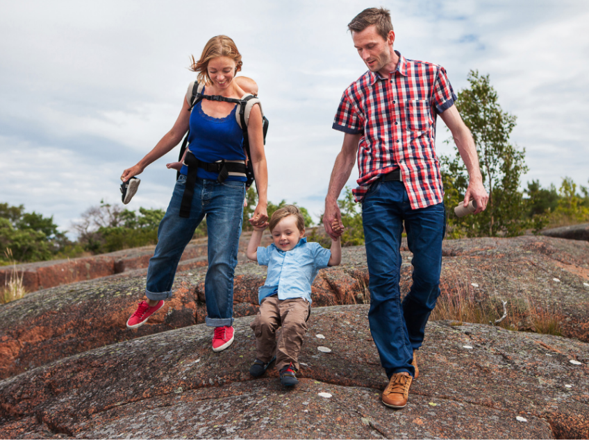 Familj med två barn promenerar hand i hand på röda klippor