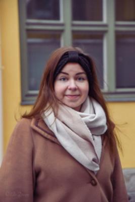 Heidi Eriksson klädd i vinterkappa och stor halsduk utanför en husfasad.