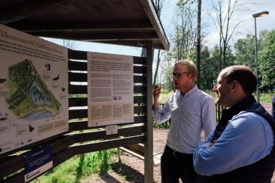 Virginijus Sinkevičius och Anton Nilsson står vid en informationstavla vid nabbens våtmark.