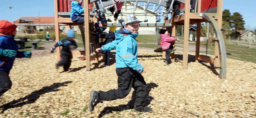 Barn som springer och leker i en lekpark med klätterställning